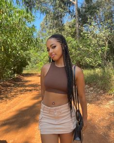 a woman with long braids walking down a dirt road