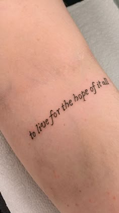 a person with a tattoo saying to live for the hope of all on their arm