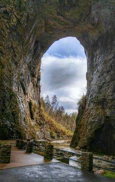 the entrance to a cave with a river running through it