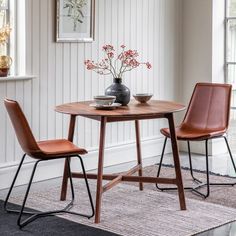 a small table with two chairs and a vase on top of it in front of a window