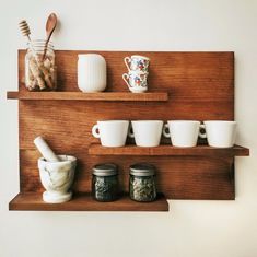 there are many cups and mugs on the shelf