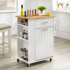 a pink kitchen cart with two drawers and some bottles on it in front of a window