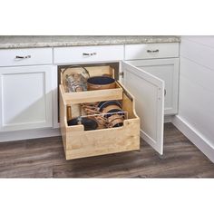 an open drawer in the middle of a kitchen with dishes and utensils inside