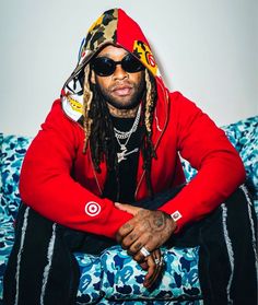 a man sitting on top of a blue couch wearing sunglasses and a red hoodie