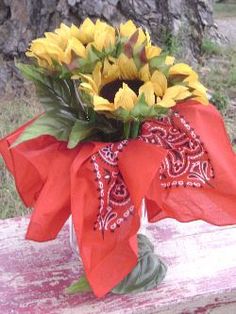 a vase filled with yellow flowers on top of a wooden bench