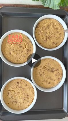 four white bowls filled with food sitting on top of a baking tray next to a green leaf