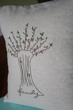 a white pillow with a tree embroidered on it