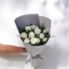 a bouquet of white roses is held by a woman's hand on a white background