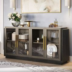 a sideboard with glass doors and gold handles in a living room area, next to a painting on the wall