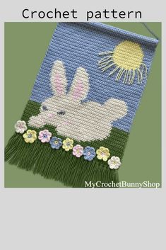 a crocheted bag with an image of a bunny in the grass and flowers on it