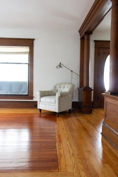 a living room with hard wood floors and a white chair in front of a window