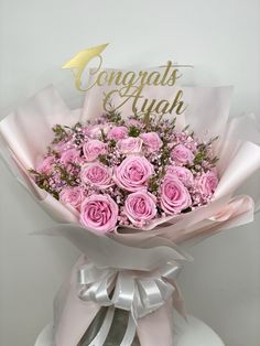 a bouquet of pink roses is wrapped in white paper and the words congrats & ahah are written on it