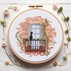 a cat sitting on a window sill in front of a brick wall with flowers