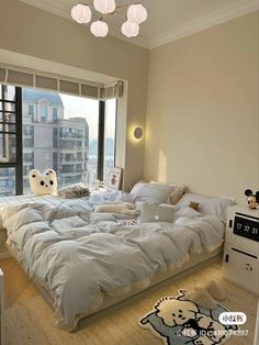 a bedroom with a large bed and lots of pillows on the floor next to a window