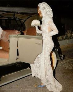 a woman in a wedding dress getting out of a car