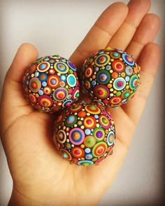 three colorful balls are in the palm of someone's hand