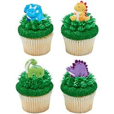 four cupcakes with green frosting and dinosaur toppers on them, all decorated in different colors