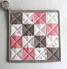 a pink and gray patchwork quilted placemat with rope on the edge,