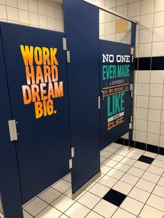 two blue stalls with words on them in a bathroom