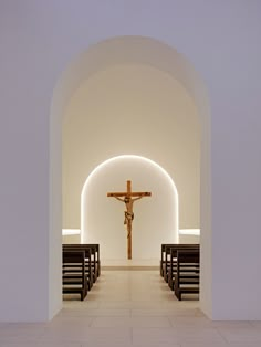 an empty church with benches and a crucifix in the center, all lit up