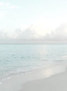 two people walking on the beach with an umbrella