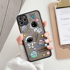 a woman holding up her phone case with an image of astronauts and planets on it