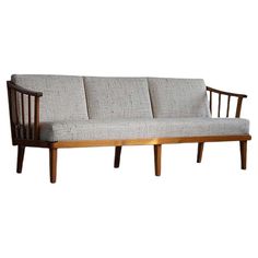 a wooden couch with grey upholstered fabric on the back and armrests