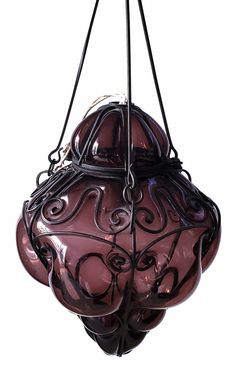 a purple vase hanging from a black metal hook on a white background with an intricate design in the center