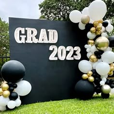 the graduation sign is decorated with balloons and streamers in black, white, and gold colors