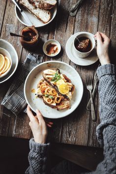 a person sitting at a table with plates of food in front of them and coffee on the side