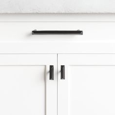 a white cabinet with two black handles on it