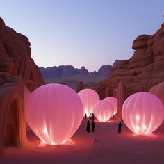 people standing in the desert with large pink lanterns lit up at night and onlookers watching