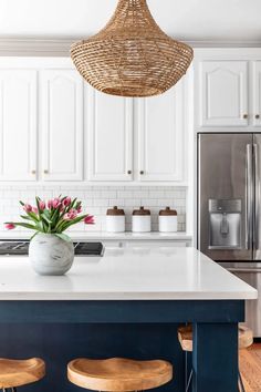 a kitchen island with two stools and a basket hanging from the ceiling over it