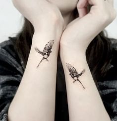 two small birds on both wrist tattoos, one is black and the other is white