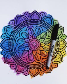 a pen is sitting on top of a drawing paper with an intricate design in the middle