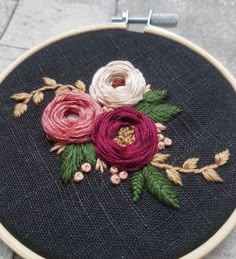 a close up of a embroidery on a piece of cloth with leaves and flowers in it