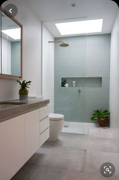 a bathroom with a toilet, sink and shower in it's center wall is shown