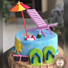 a birthday cake decorated with a beach scene and flip flops on the sand under an umbrella