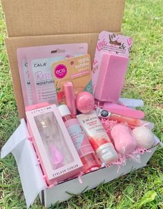 an open box with various items in it on the green grass, including soaps, lip balm, and more