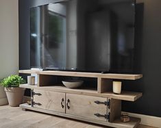 a flat screen tv sitting on top of a wooden entertainment center next to a potted plant