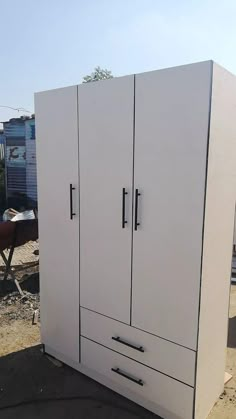 two white cabinets sitting on top of a dirt field