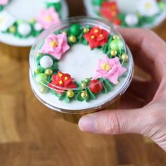 a person is holding a small container with some decorations on top of it and the lid has flowers in it