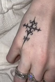 a woman's hand with a small tattoo on the middle finger and an intricate design