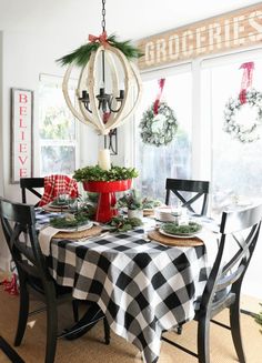 a dining room table decorated for christmas with wreaths and greenery