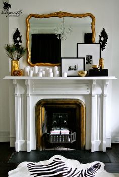 a living room with a fireplace, mirror and pictures on the mantel above it