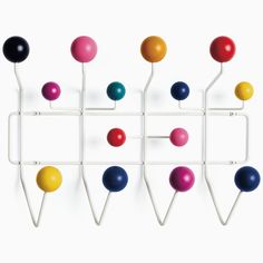 a wall mounted rack with balls and hooks on the back of it, against a white background