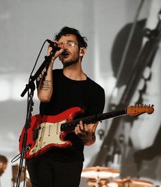 a man singing into a microphone while holding an electric guitar in front of his face