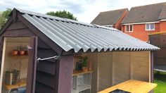 a small shed with a metal roof and shelves on the outside