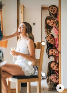 a group of women sitting next to each other on top of a wooden chair in front of a mirror