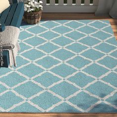 a blue area rug with white trellis on the front and back sides, sitting on a wooden deck